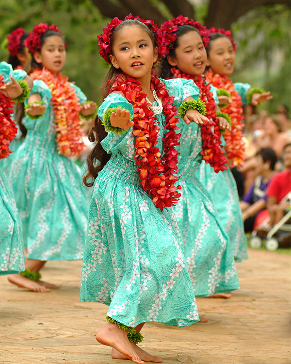 Young girls wearing matching dresses perform a traditional dance.