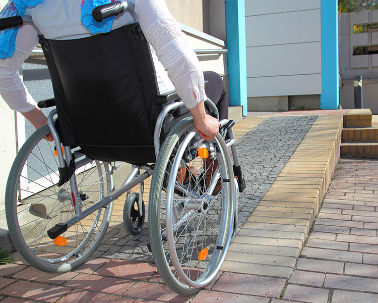 A person in a wheelchair ascends a ramp.