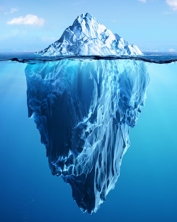 An iceberg floats in the water. Most of it is submerged.