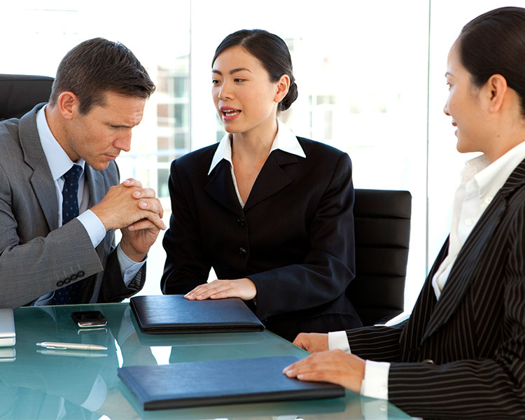 Two women and a man talk in a conference room.