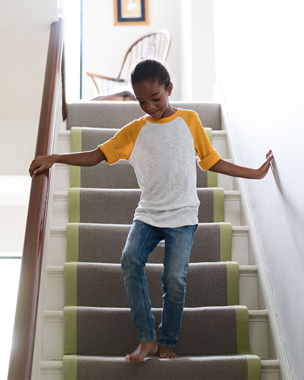 A young girl walks down stairs.