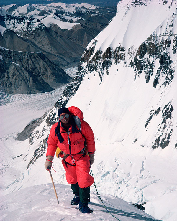 A climber on a mountain above a valley.