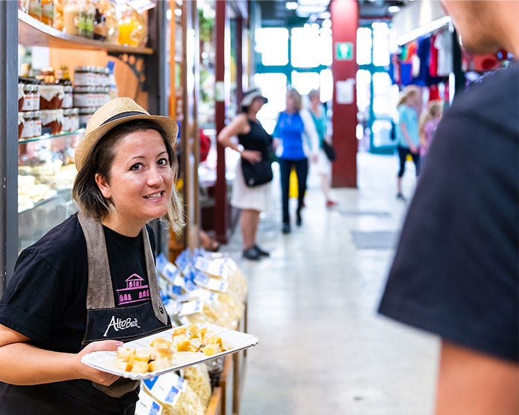 A woman holds a tray of free food samples for customers.