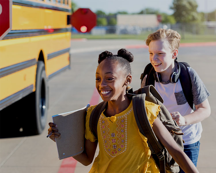 A boy and a girl running to the school bus