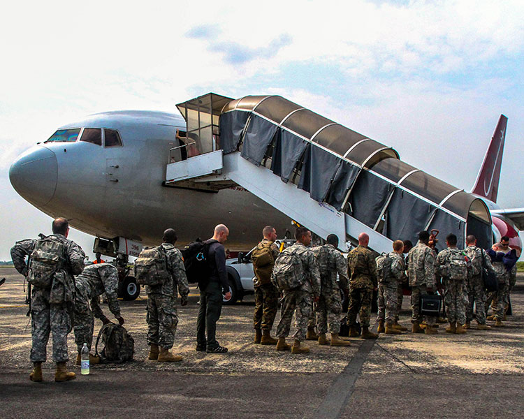 A line of soldiers boarding a military aircraft