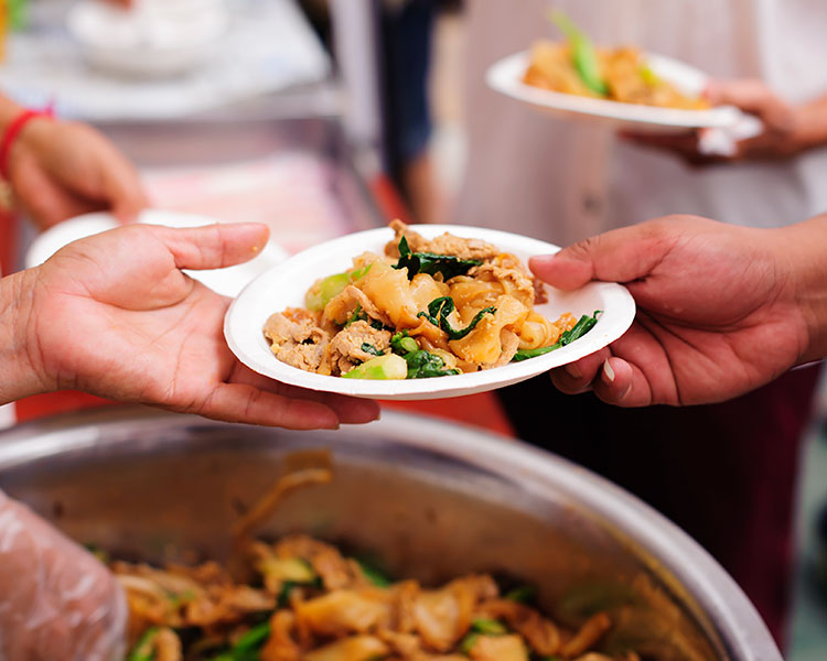 One person passing a plate full of food to another