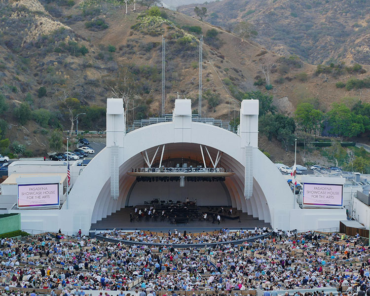 People performing at an amphitheater with a large crowd