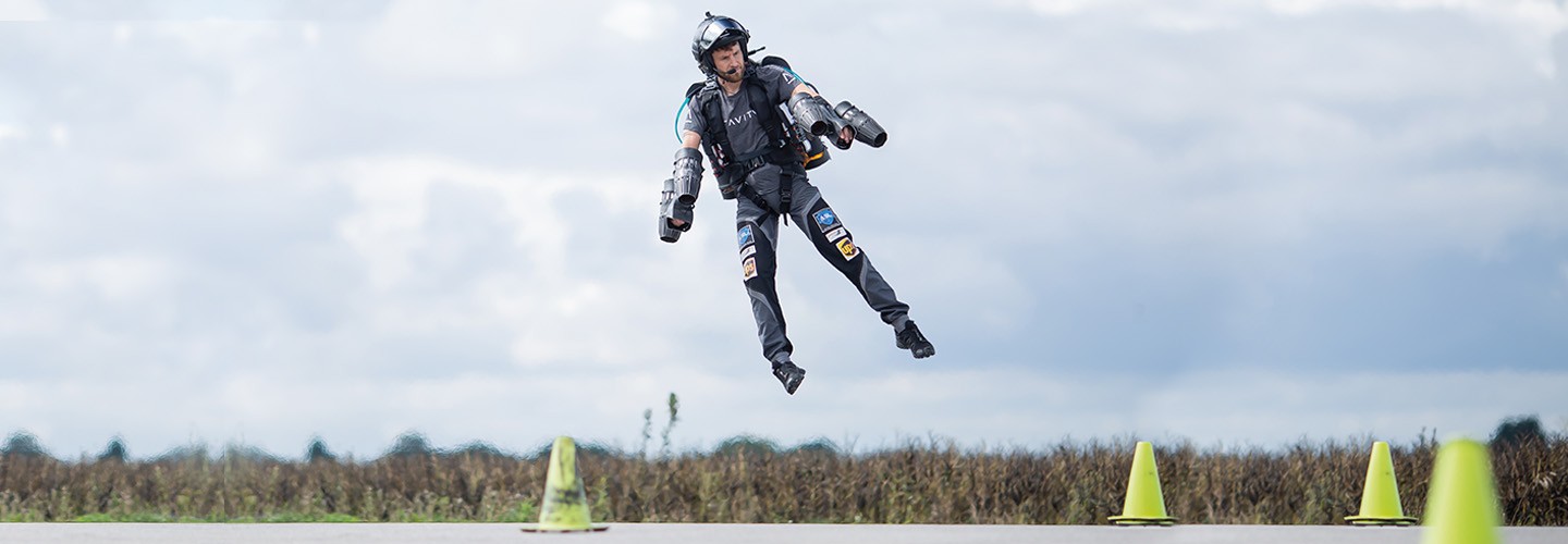 Photo of a person wearing a jet pack and flying over land