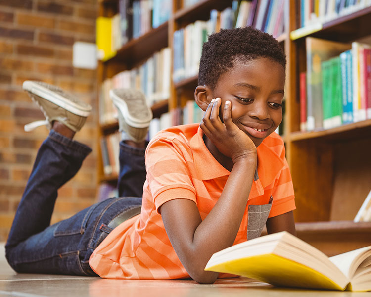 Photo of a student smiling and reading a book