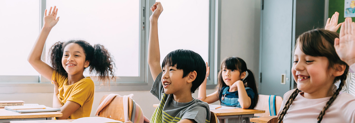 Image of students raising their hands in a classroom