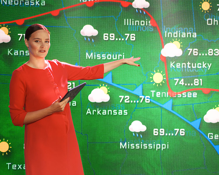 Person in front of a green screen displaying weather in different areas