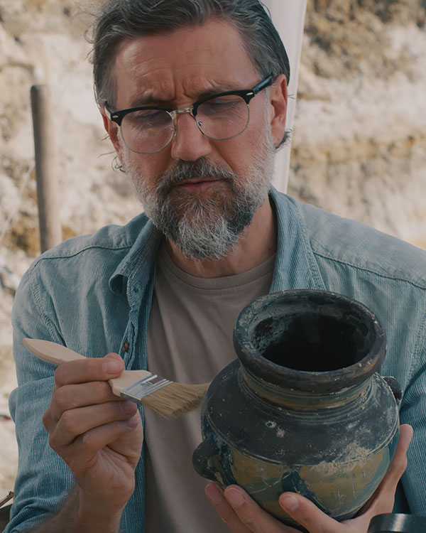 A person using a brush to clean off a ceramic piece