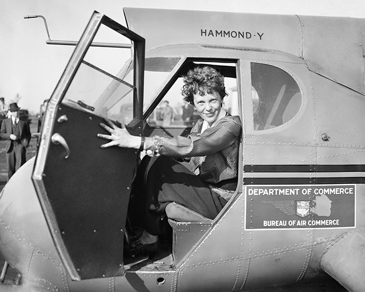 Black & white photo of Amelia Earhart in the passenger seat of the Department of Commerce plane