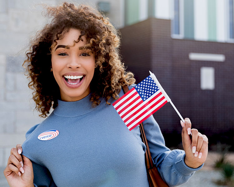 Person wearing an "I Voted" sticker and holding a small American flag