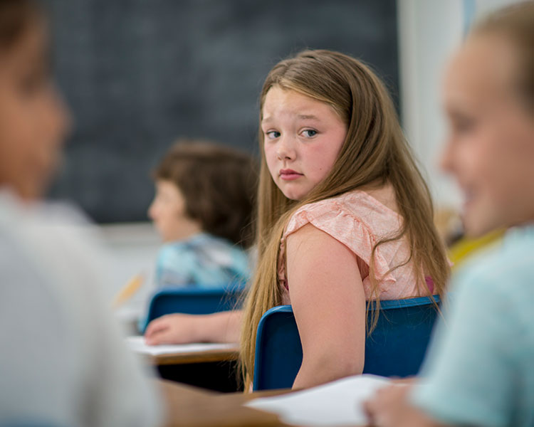 Image of a student turning around in her chair to look back to other classmates