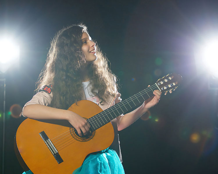 Photo of a person playig guitar on a stage