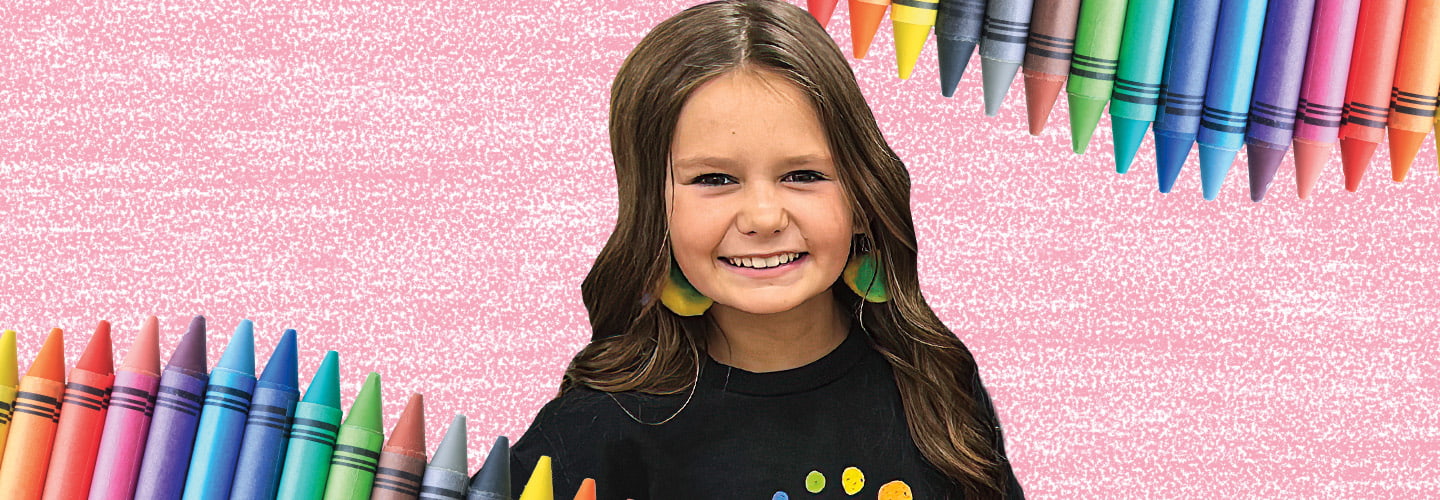 Photo of a kid smiling against a backdrop of colorful crayons