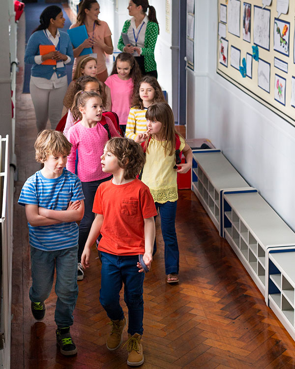 Photo of young students and teachers walking down a hallway