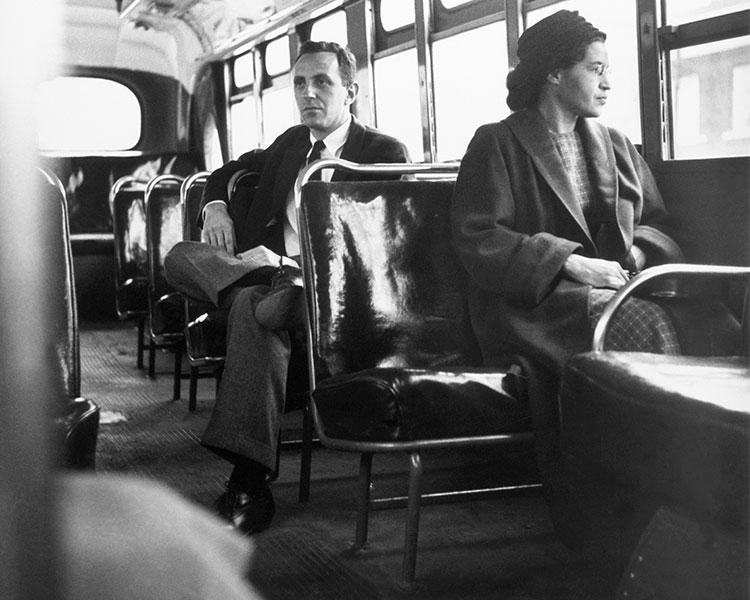 Black & white photo of Rosa Parks sitting at the front of a bus