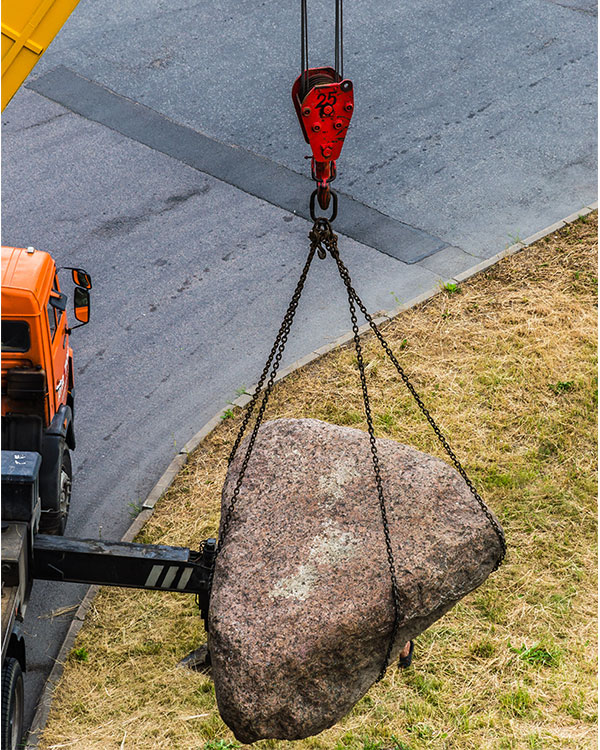 Photo of a construction truck lifting a large boulder