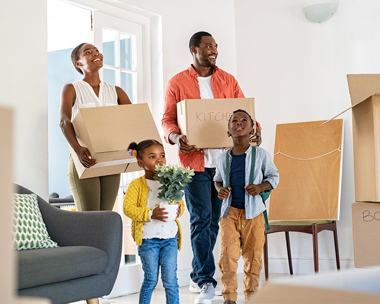 Photo of a family walking into their new home with boxes