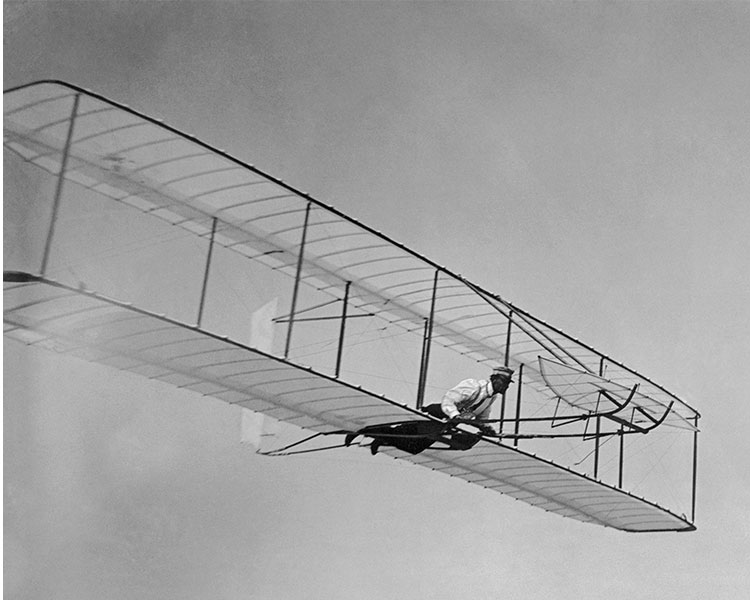 Black & white photo of Wright Brothers experimenting with their plane