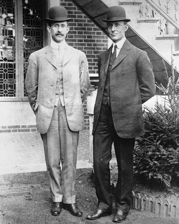 Black & white photo of the Wright Brothers posing & wearing suits