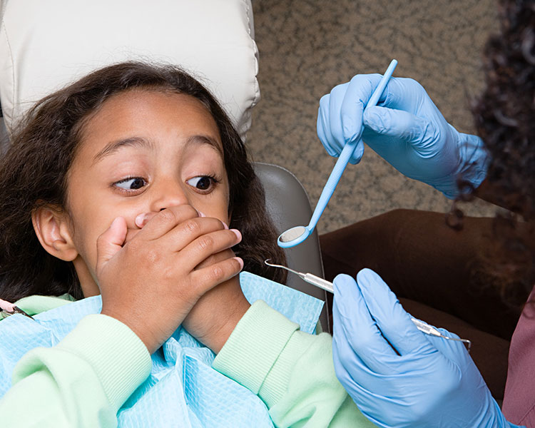 Photo of a nervous kid covering their mouth from the dentist