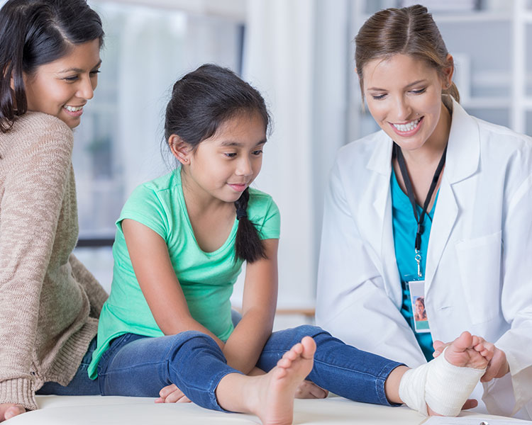 Photo of a doctor putting a bandage wrap on a girl&apos;s ankle