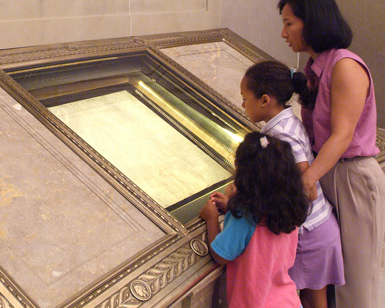 Image of a family looking at an old document on display in a museum