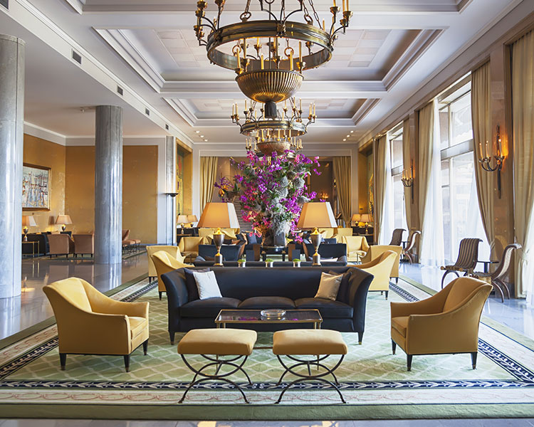 Image of an interior room of a very fancy home along with big windows and chandeliers