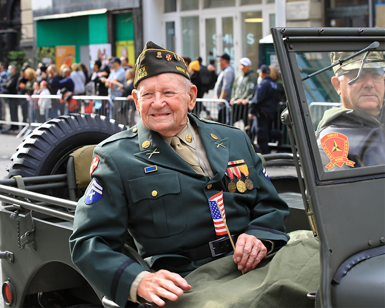 Image of an older Veteran wearing their uniform while participating in a parade