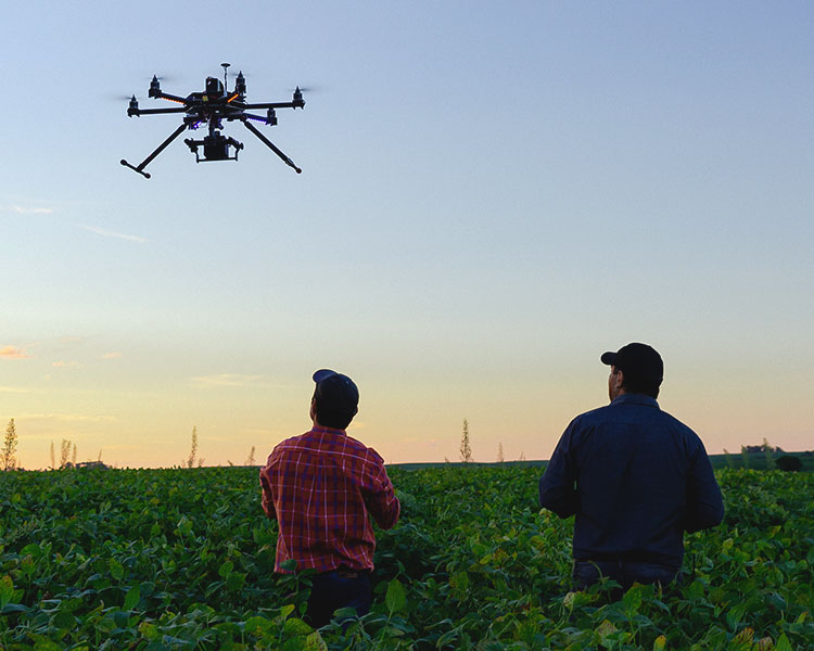 Photo of two people in a field controlling a large drone