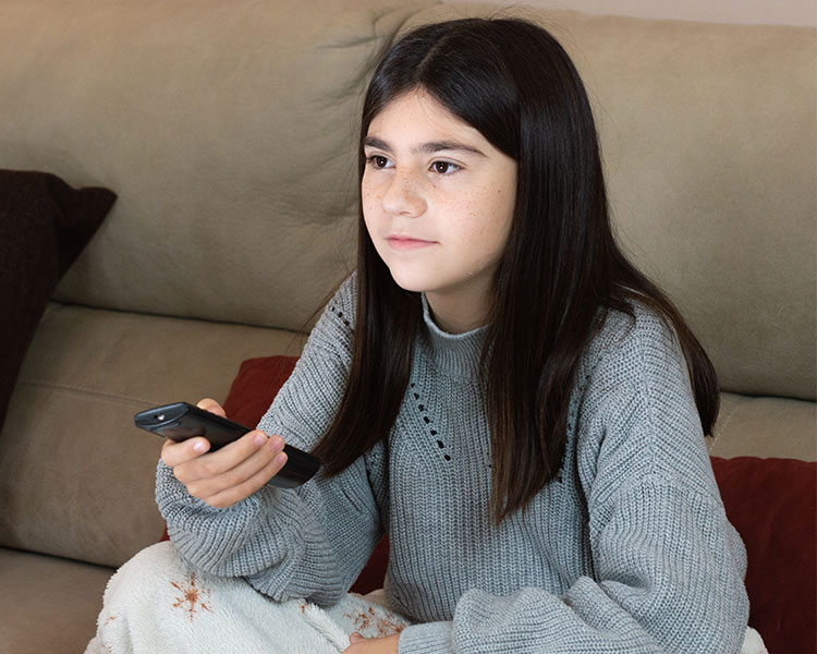 Photo of a kid sitting on couch while holding tv remote