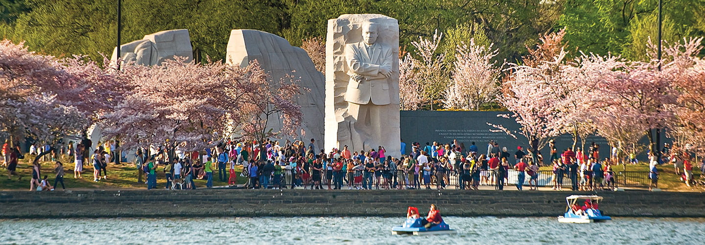 the MLK Jr memorial seen from a river with many tourists in front